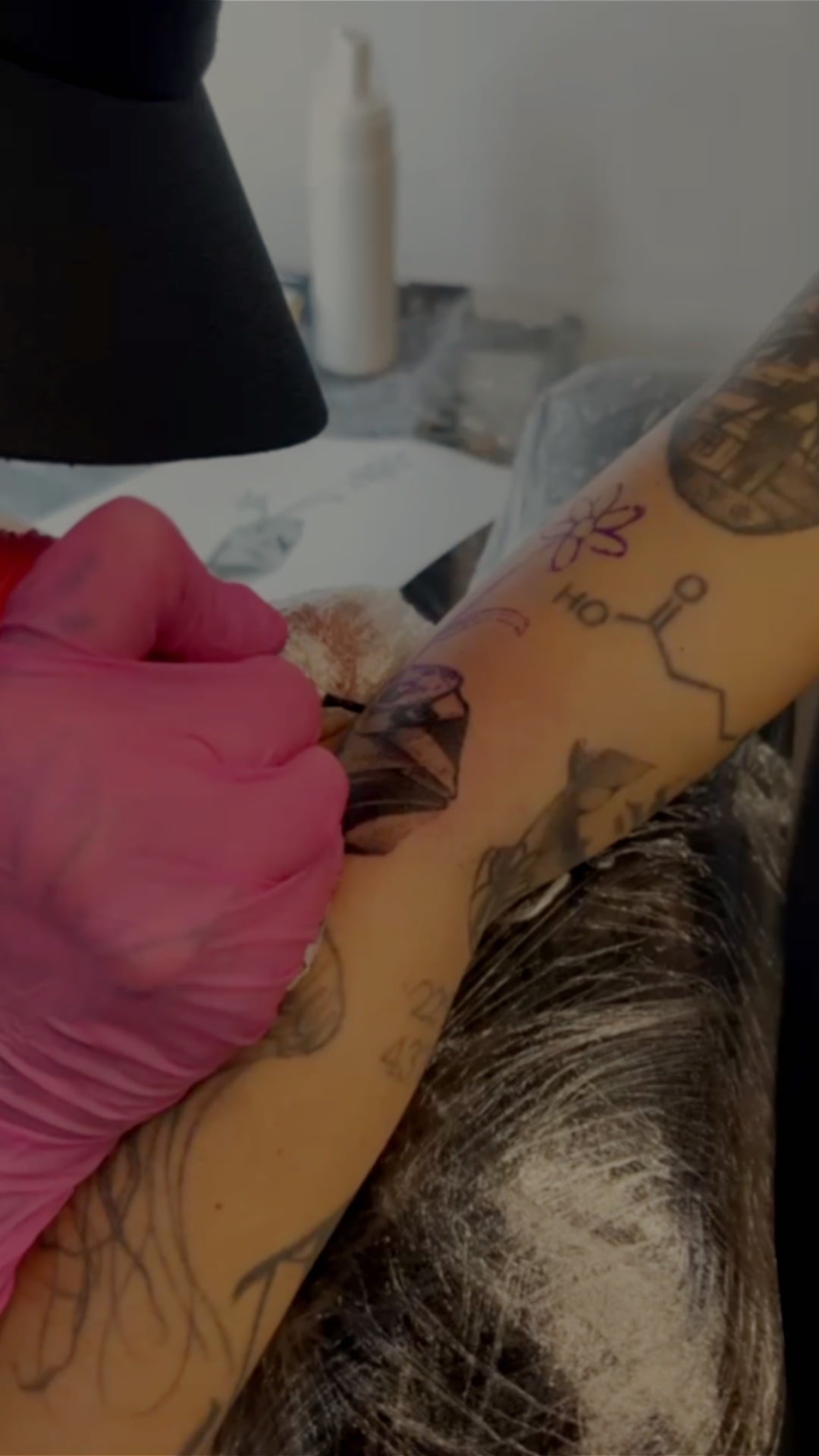 Maria tatuando à mão livre o braço de uma cliente